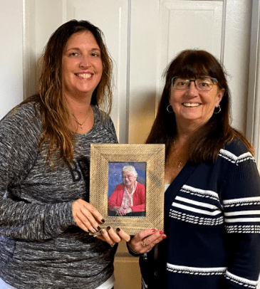two women holding photo of elderly woman