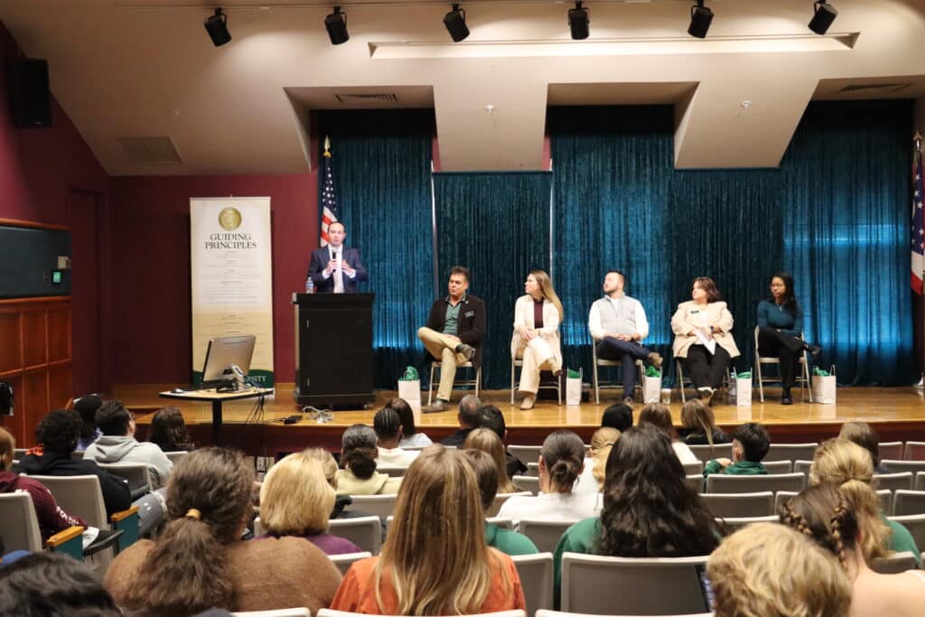 Person on panel talking in front of group of people