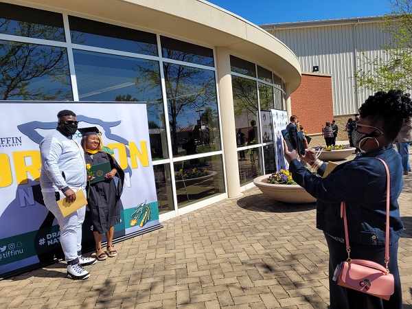 graduate and family member posing outside