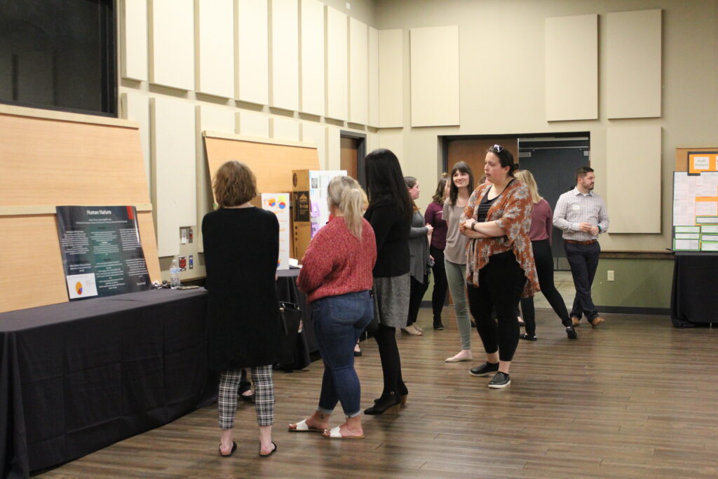 students and faculty and staff looking at posters at the research conference