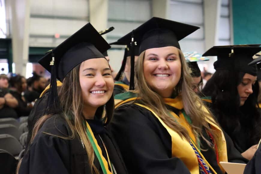 two smiling students at graduation