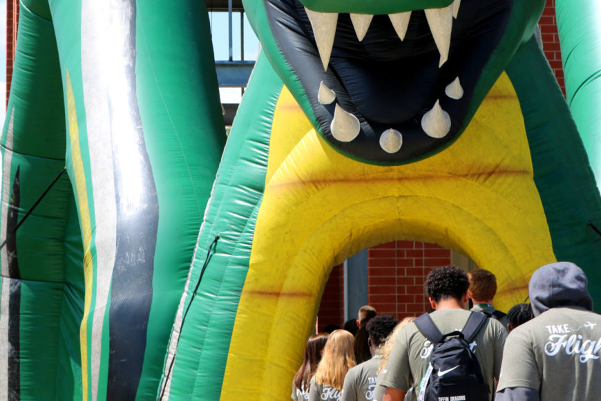 parade of students marching towards convocation through inflatable dragon tunnel