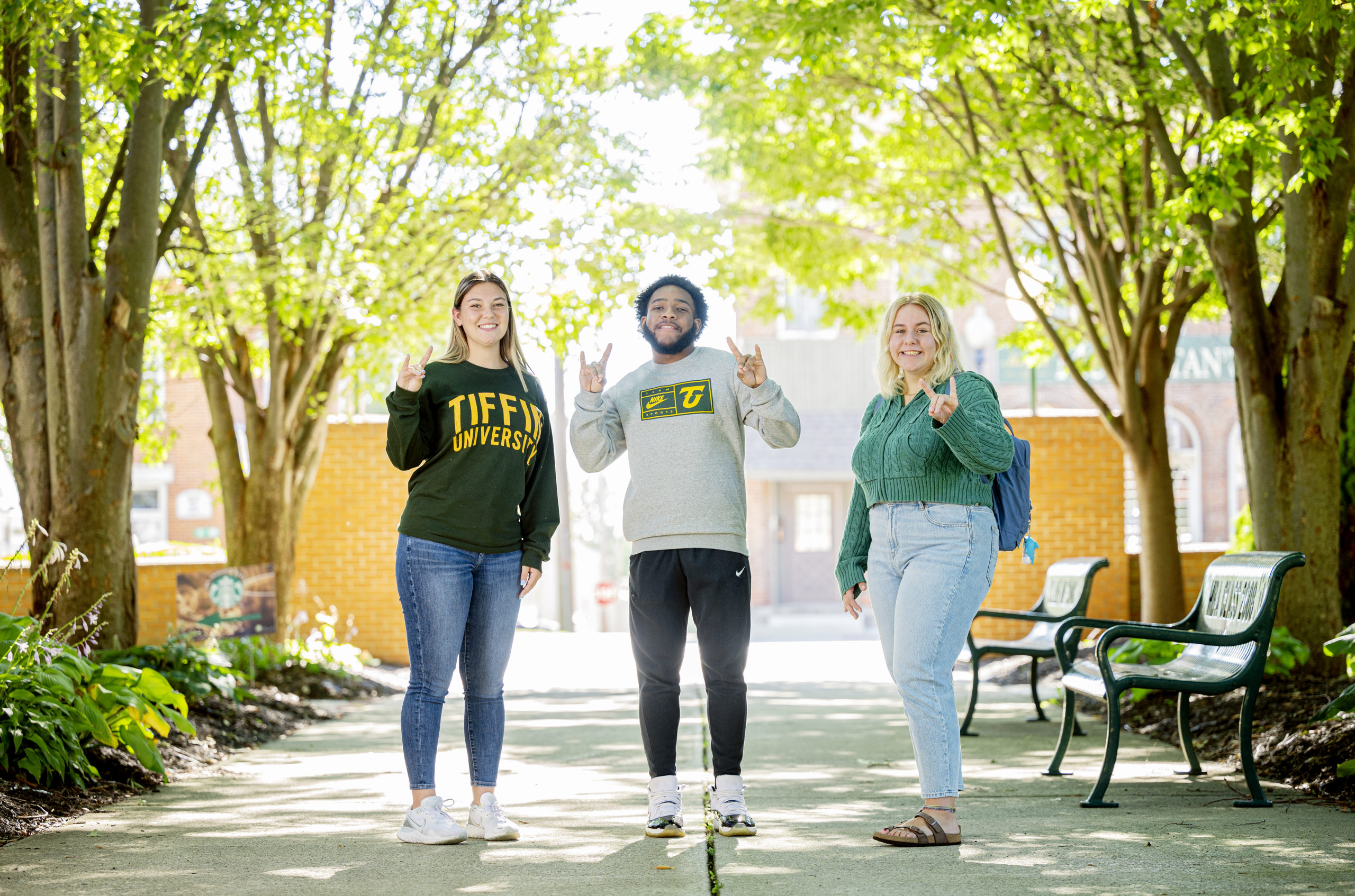 Three smiling students hold up a dragon sign