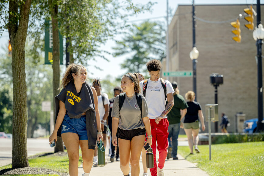 students walking on side walk smiling and talking
