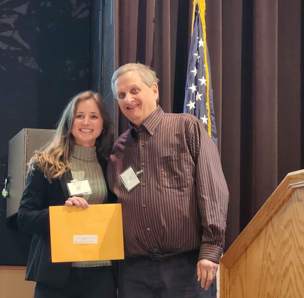 abbie smiling with steven hurwitz and her award