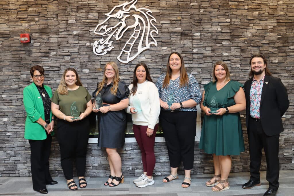 award winners standing and smiling with their awards