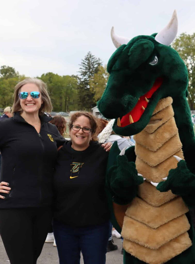 smiling alumni with blaze at football game