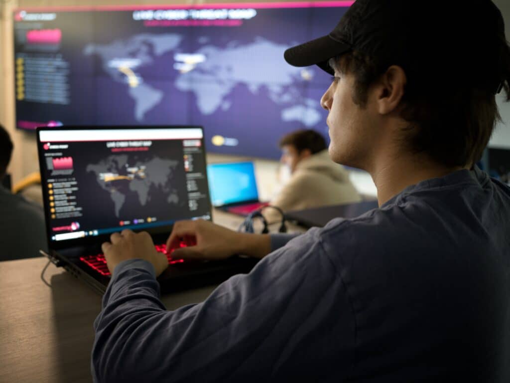 Cybersecurity student viewing live cyber threat map on laptop