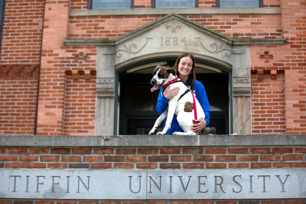 student with dog in front of main hall