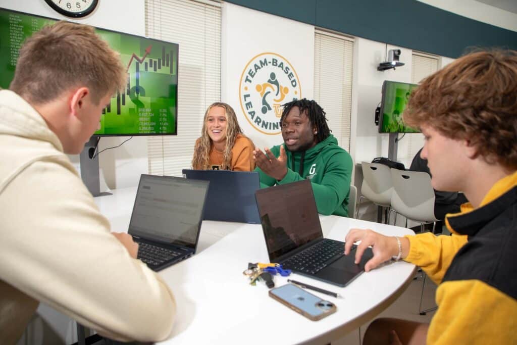Computer science degree students on laptops in group project