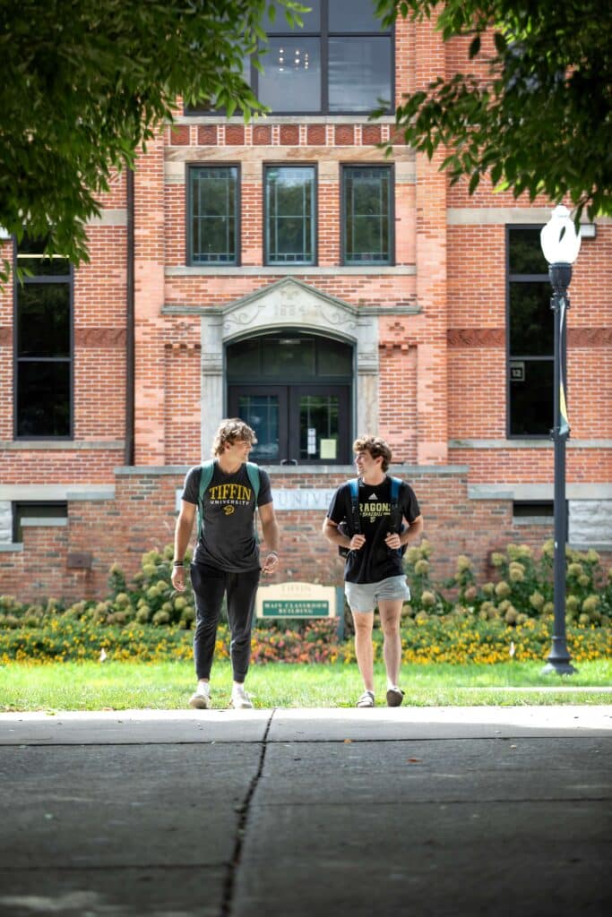 two students walking on pathway in front of main